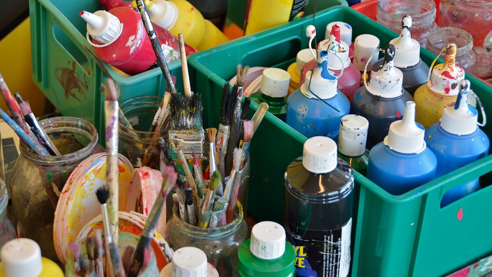 Maling og pensler i kasser på et bord
