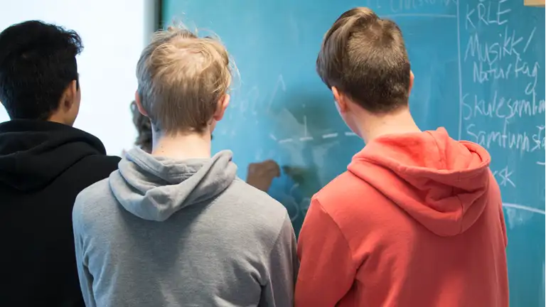 Elever i en gruppe foran en tavle 
