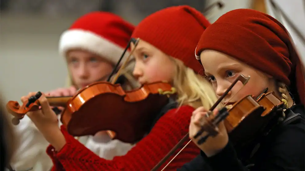 Børn fra musikskolen spiller violin med nissehuer på