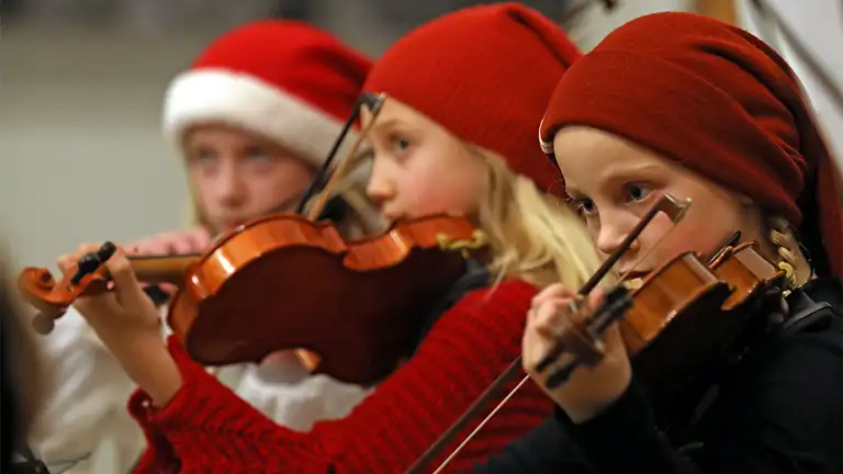 Børn spiller violin iført nissehuer