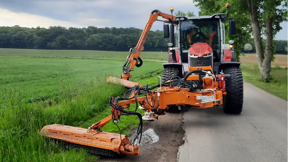 Billede af en rød traktor med en græsklipper monteret foran