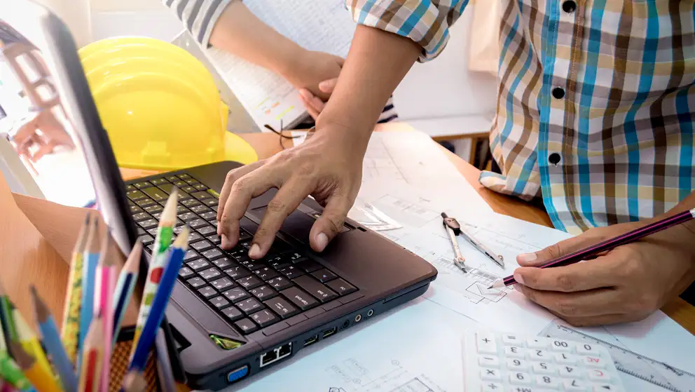 Billede af mand, der kigger på byggetekniske tegninger ved en bærbar computer