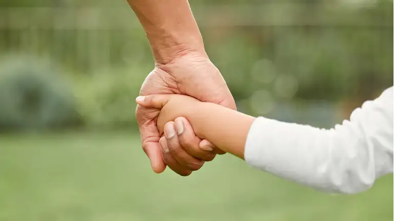 Voksen og barn hånd i hånd