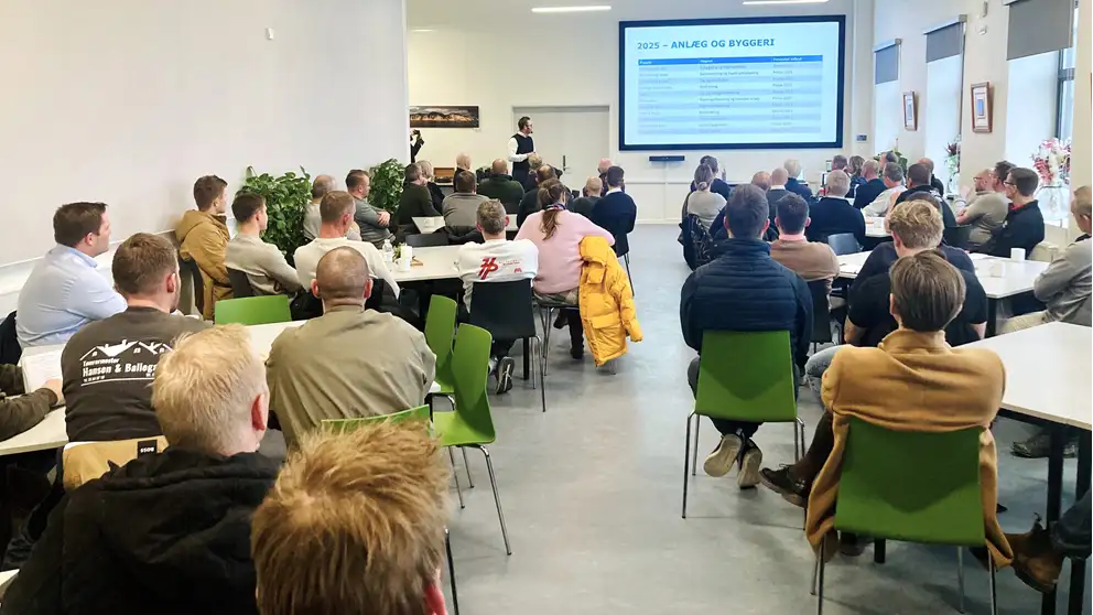 Billede af mennesker i en sal, der sidder ved borde og ser en præsentation