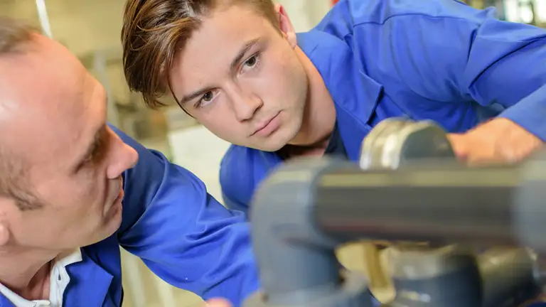 Ung mand kigger på rør med voksen medarbejder