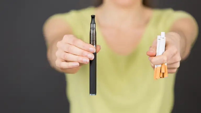 Kvinde der holder en vape og cigaretter