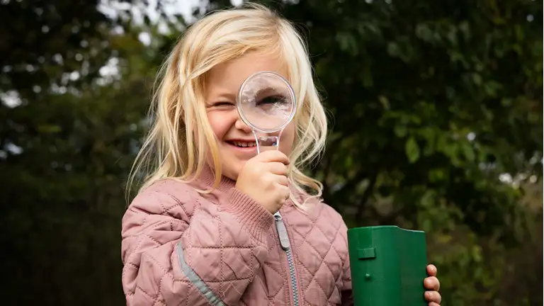 Billede af en børnehave-pige med et forstørrelsesglas