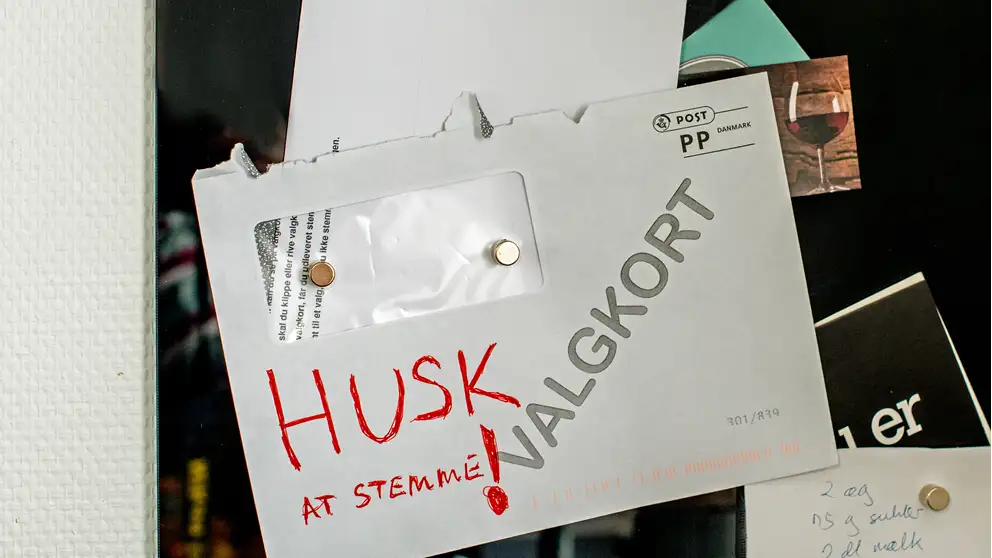 Billede af en kuvert med et valgkort, der hænger på en opslagstavle