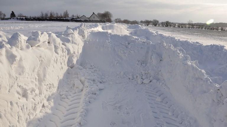 Billede af en vej, der er ved at blive gravet fri af en stor snebunke